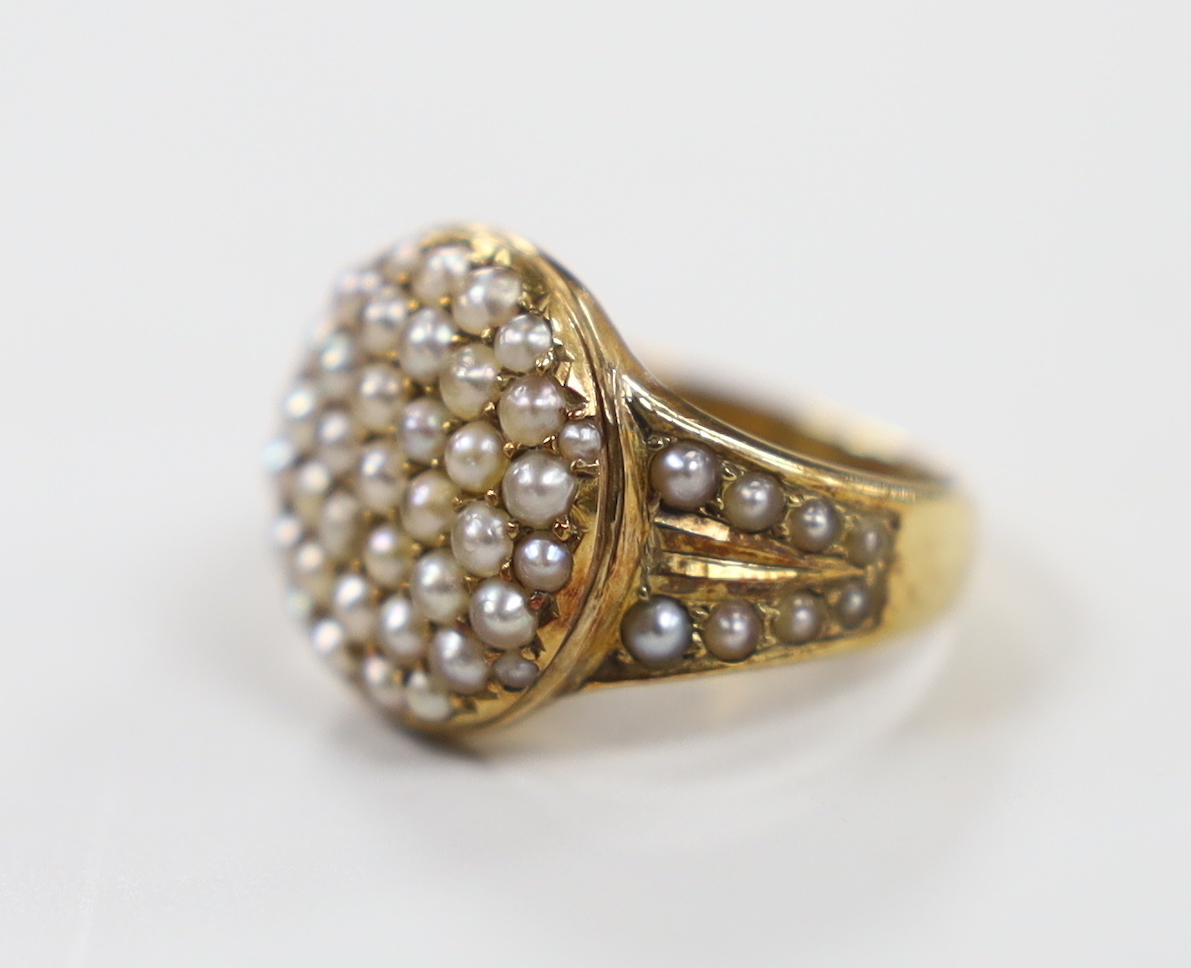 An Edwardian 15ct and seed pearl cluster set dress ring, with seed pearl set shoulders, size J/K, gross weight 5.6 grams, in original box.